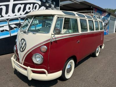 un minibus Volkswagen rouge et blanc garé devant un immeuble