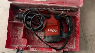 une boîte à outils rouge contenant une perceuse et un cordon d'alimentation