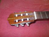 une image montrant un gros plan d'une guitare posée sur une surface rouge