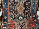 une photo d'un tapis bleu et rouge posé sur une chaise dans une pièce