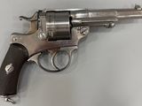 un vieux revolver avec une poignée en bois sur une surface blanche