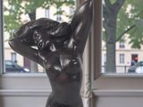 a statue of a woman sitting on a table in front of a window