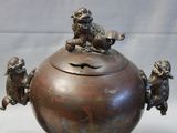 a bronze teapot with monkeys on top of it