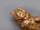 a small gold bird sitting on top of a table