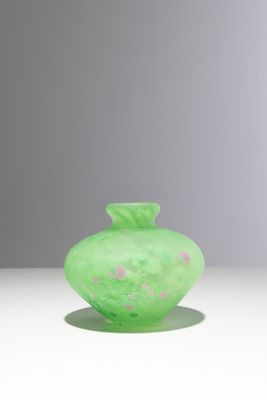 un vase en verre vert orné de fleurs roses, posé sur une surface blanche