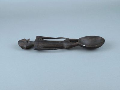 une vieille figurine en bronze représentant un homme tenant une cuillère et un repose-cuillère
