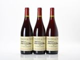 three bottles of red wine sitting on top of a white table