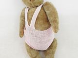 un ours en peluche marron portant un gilet rose tricoté