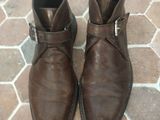 pair of brown leather boots with buckles on a brick floor