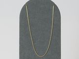 un collier à chaîne en or posé sur un présentoir noir