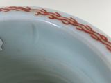 a close up of a white vase with red writing on it