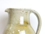 a white pitcher sitting on a table with a white background
