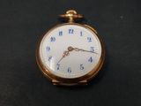 une montre de poche en or avec un cadran bleu sur fond noir