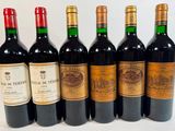 six bottles of wine are lined up in a row on a white surface