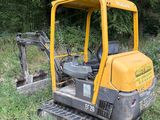 a small yellow excavator sitting in the middle of a field