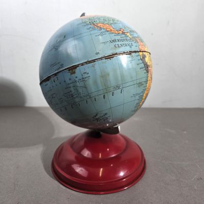 un petit globe bleu posé sur un socle rouge, sur une table