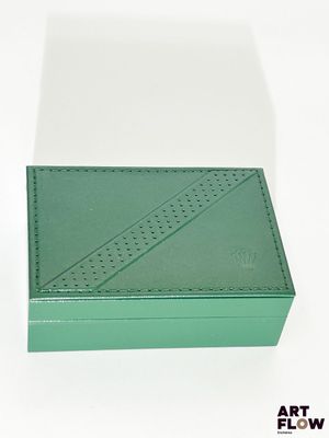 une boîte verte vide posée sur une surface blanche
