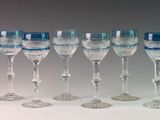 twelve wine glasses lined up in a row on a white surface