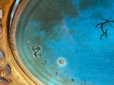 a close up of a blue and gold plate with a bird on it