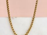 une photo d'un collier à chaîne en or posé sur une surface en marbre
