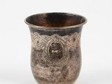 une tasse en argent posée sur une surface blanche