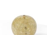 boule de verre jaune posée sur une surface blanche, sur fond blanc