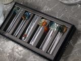 four glass spoons in a black box on a table