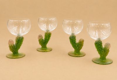 quatre verres à vin ornés de tiges et de feuilles vertes, posés sur un fond beige