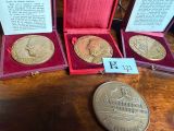 three gold and silver coins are in a red case on a table