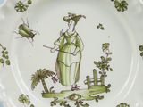 a green and white plate with a lady and a bird on it