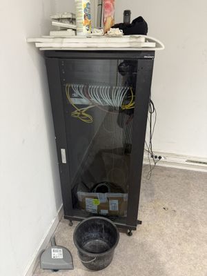 une armoire noire avec une porte vitrée et un seau d'eau