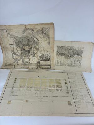 deux vieilles cartes posées sur une table, avec un stylo et du papier
