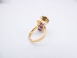 a close up of a yellow gold ring with a purple stone