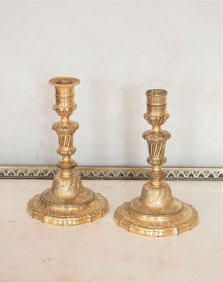 une paire de bougeoirs anciens en laiton posés sur une table dans une pièce
