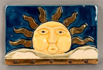 a ceramic tile with a sun on it ' s face