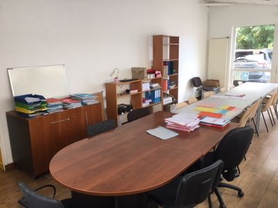une longue table avec des chaises, dans une pièce où se trouvent de nombreux livres