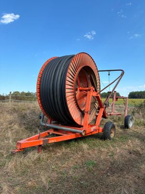 un gros tuyau orange posé sur une remorque dans un champ