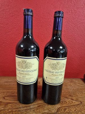 deux bouteilles de vin posées sur une table en bois, près d'un mur rouge