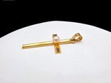 a gold cross with a pearl on it on a white surface