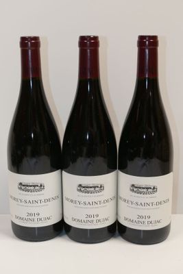 trois bouteilles de vin sont alignées sur une surface blanche