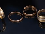 three different types of gold rings on a black surface