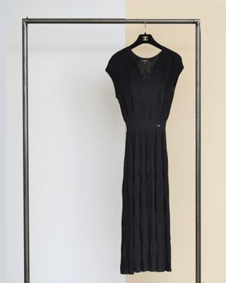 une robe noire suspendue à un portant devant un mur blanc