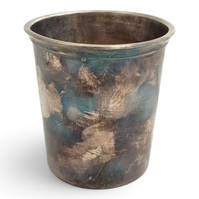 une tasse en métal posée sur une surface blanche