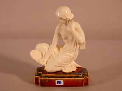 a figurine of a woman sitting on top of a book