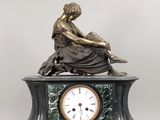 une statue de femme assise au sommet d'une horloge