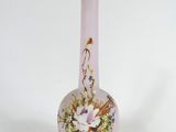 un vase en verre rose orné de fleurs, posé sur une surface blanche