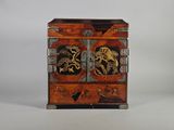 une image représentant un petit meuble en bois dont la porte est ornée d'un motif de dragon