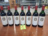 six bouteilles de vin rouge sont alignées sur une table