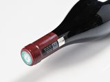 underside view of a bottle of wine with a red cap on a white surface