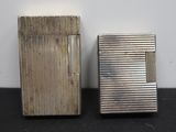 two silver lighters sitting next to each other on top of a table